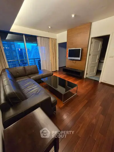 Modern living room with sleek leather sofa and city view from large windows.