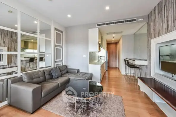 Modern living room with sleek design, featuring a cozy gray sofa, stylish coffee table, and open kitchen layout.