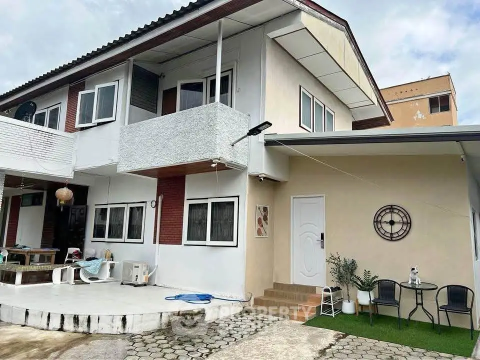 Charming two-story house with modern exterior and cozy outdoor seating area.