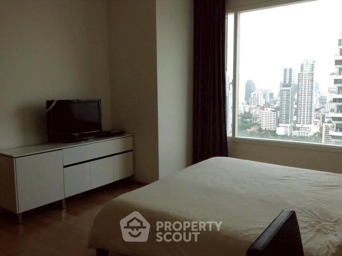 Modern bedroom with city view, featuring sleek furniture and large window for natural light.