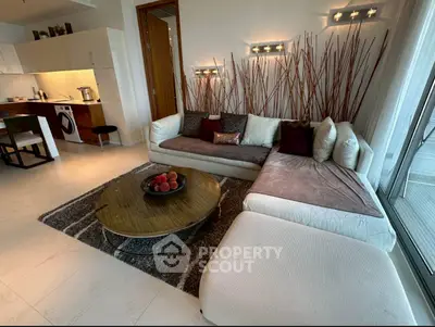 Modern living room with stylish decor and open kitchen layout, featuring cozy seating and elegant lighting.