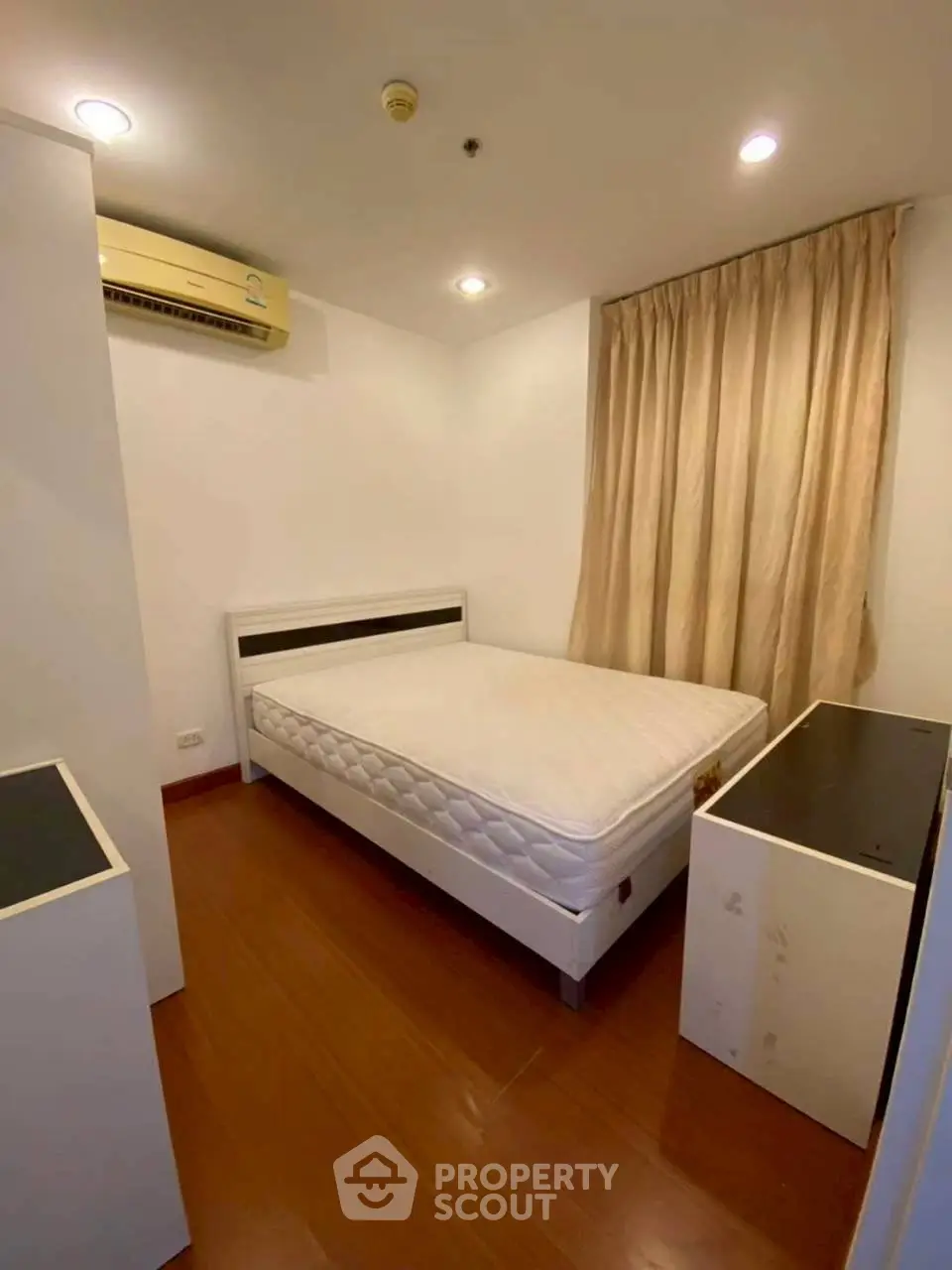 Cozy bedroom with wooden flooring and air conditioning in modern apartment