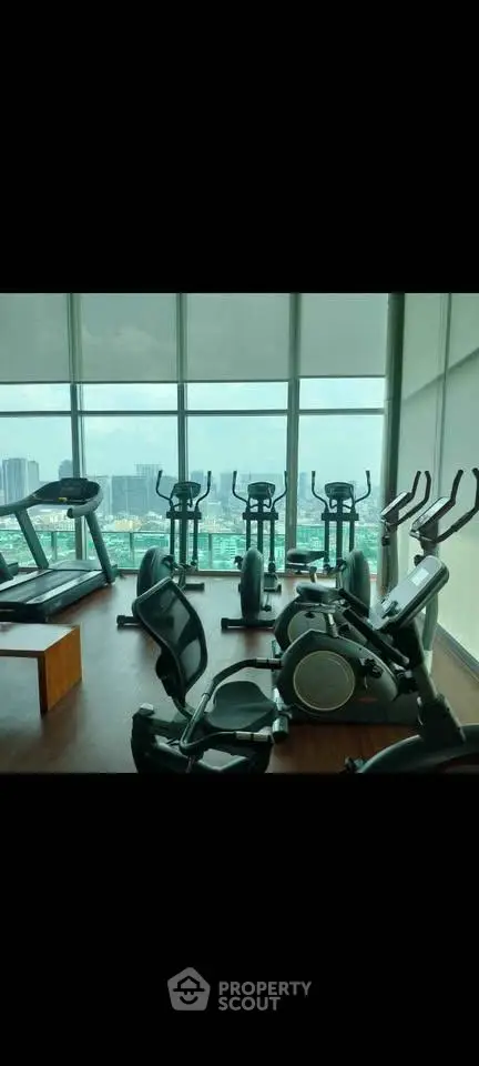 Modern gym with city view and state-of-the-art exercise equipment in high-rise building.
