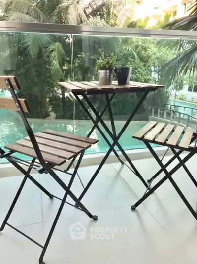 Charming balcony with pool view, featuring modern outdoor furniture and lush greenery.