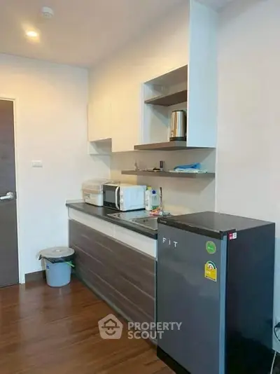 Compact kitchen with modern appliances and sleek cabinetry in a cozy apartment.