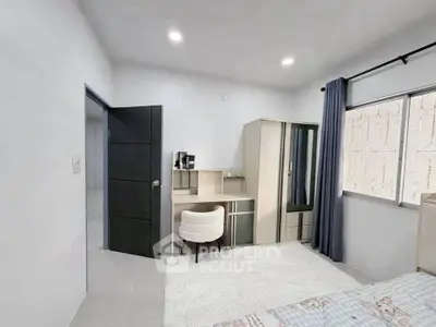 Modern bedroom with study area and large window, featuring sleek furniture and neutral decor.