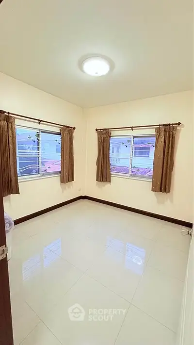 Bright empty bedroom with large windows and tiled floor, perfect for customization.