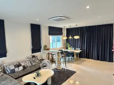 Modern living room with stylish decor and dining area, featuring cozy seating and elegant lighting.