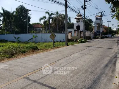 Scenic street view with lush greenery and residential buildings, ideal for real estate investment.