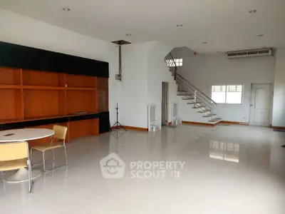 Spacious open-plan living area with modern staircase and built-in shelving.