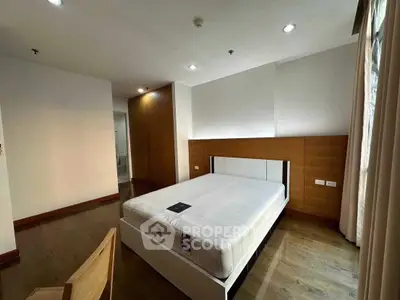 Spacious bedroom with modern design and ample natural light, featuring a comfortable bed and stylish wooden accents.