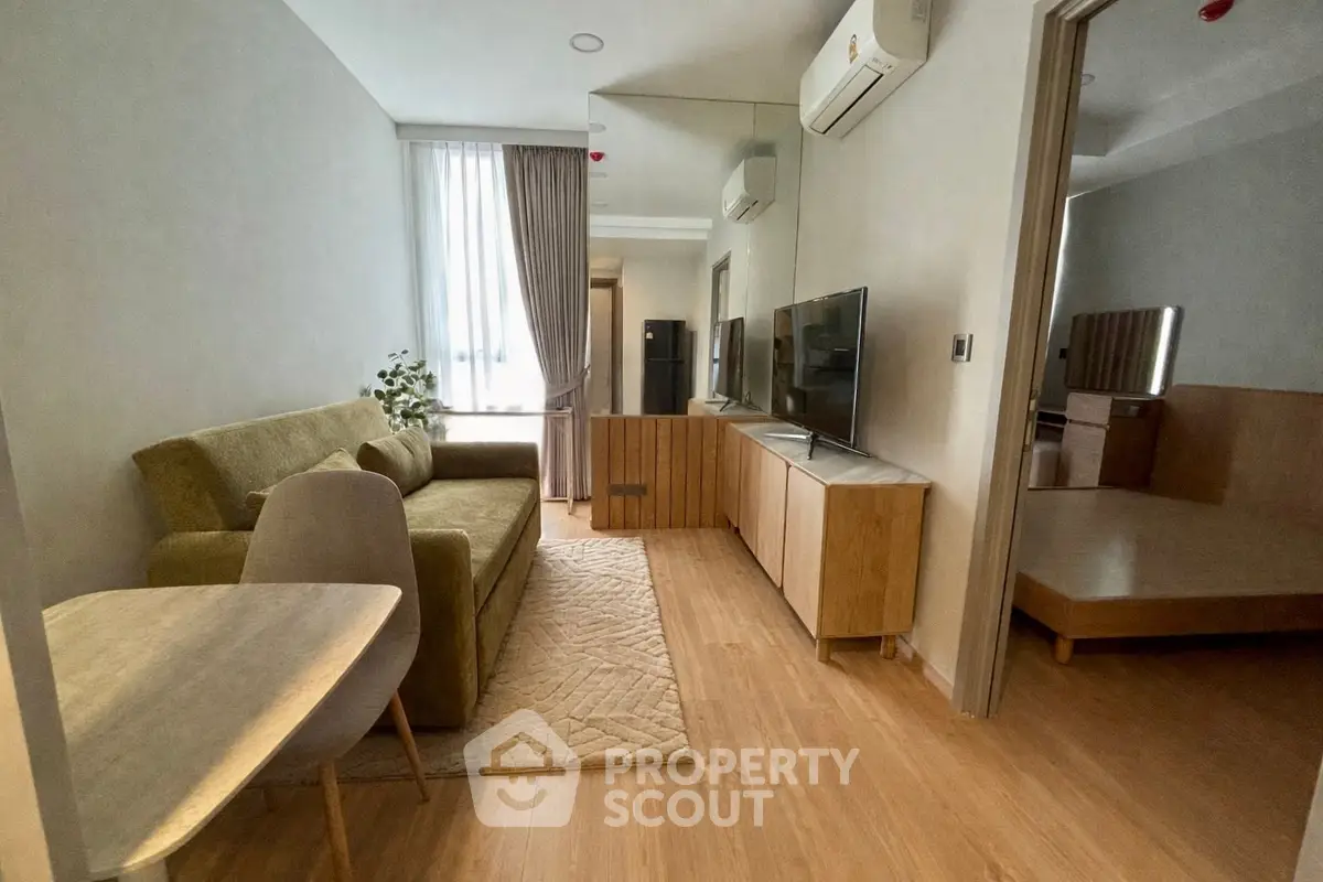 Modern living room with cozy sofa, sleek TV unit, and natural light in stylish apartment.