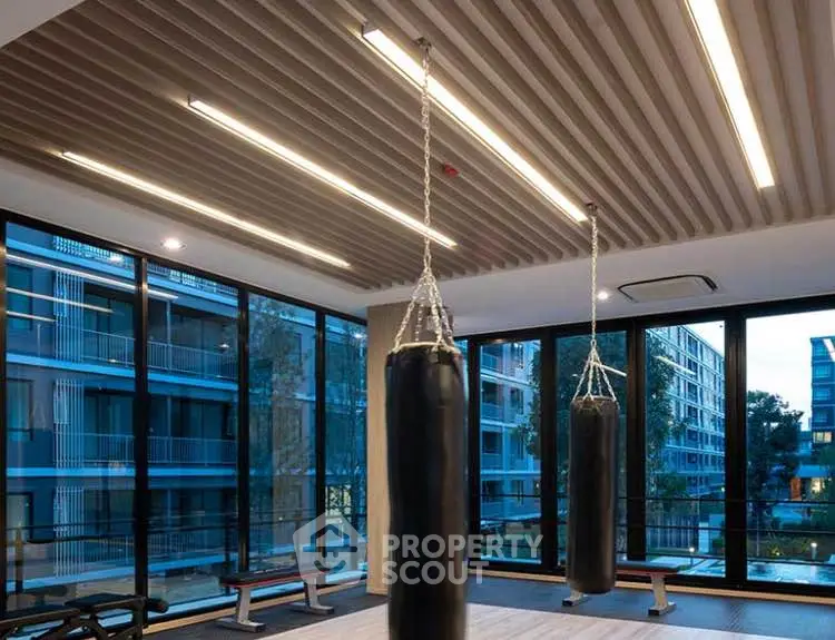 Modern gym with punching bags and large windows in luxury apartment complex.