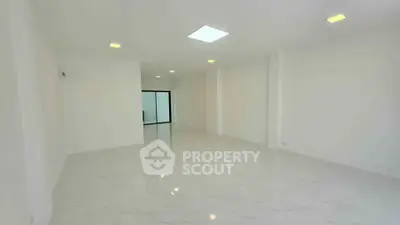 Spacious modern interior with sleek white flooring and ample natural light, perfect for versatile living space.