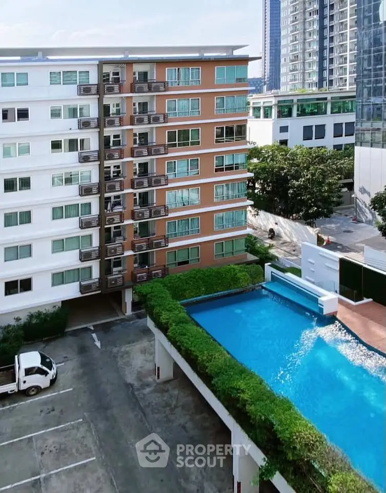 Modern apartment building with pool and parking area, ideal for urban living.