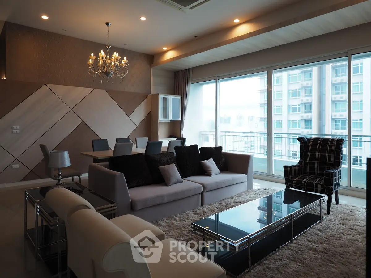 Luxurious modern living room with elegant chandelier and large windows offering stunning city views.