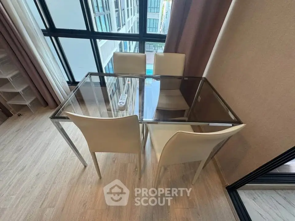 Modern dining area with glass table and beige chairs in a high-rise apartment with large windows.
