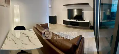 Modern living room with sleek furniture and large TV, featuring a stylish marble table and cozy brown sofa.