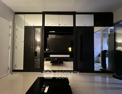 Modern living room with sleek black furniture and mirrored cabinets