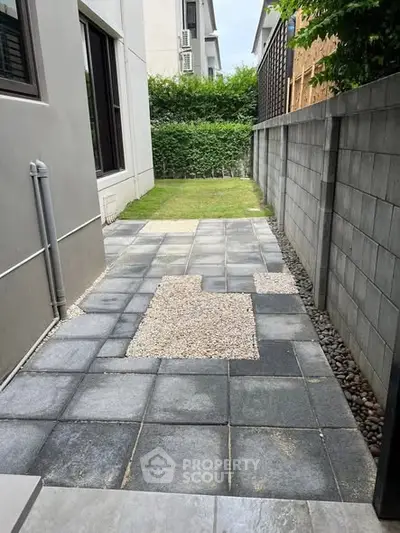 Modern backyard with paved walkway and lush green lawn