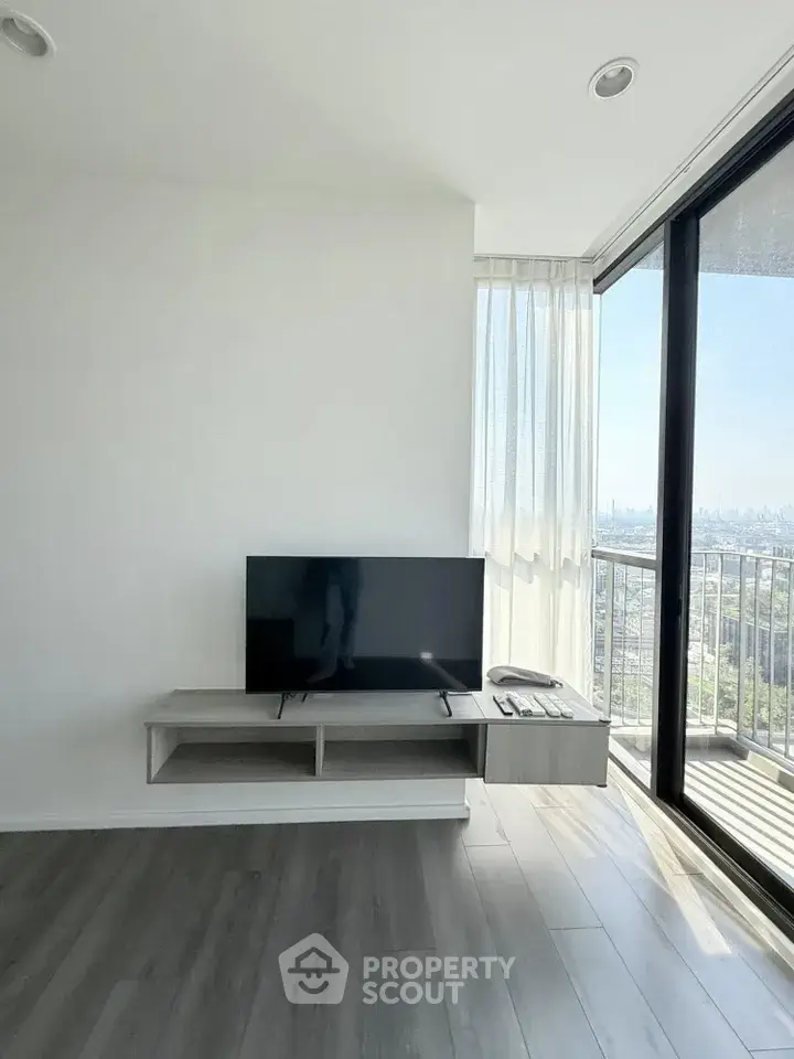 Modern living room with sleek TV stand and floor-to-ceiling windows offering stunning city views.