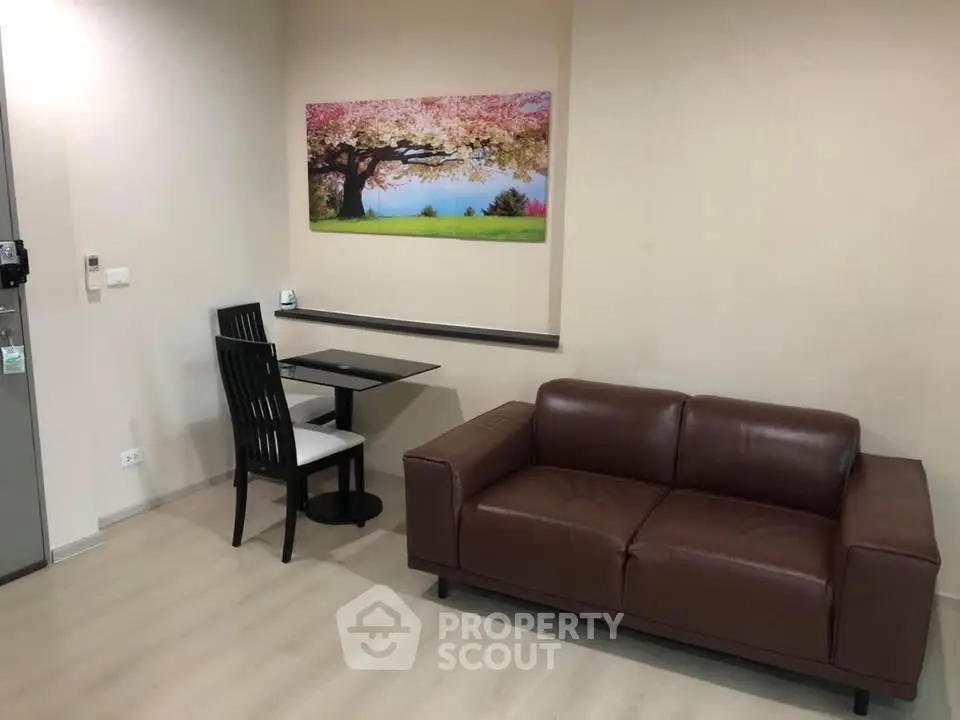 Cozy living room with brown leather sofa and dining area, featuring elegant wall art.