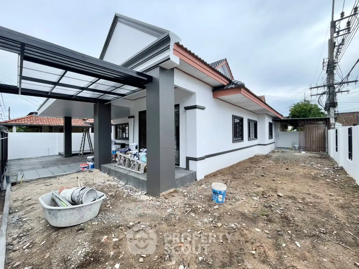 Charming single-story house with modern exterior and spacious yard under renovation.