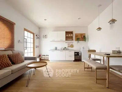 Modern open-plan living room and kitchen with minimalist decor and natural light.
