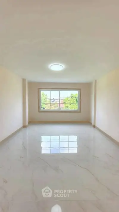 Spacious empty room with large window and glossy marble floor, offering a bright and airy atmosphere.