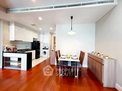 Modern open-layout kitchen and dining area with wooden flooring and sleek appliances.