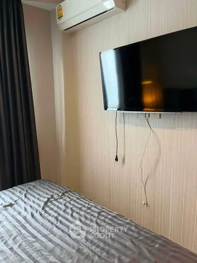 Cozy bedroom with wall-mounted TV and air conditioning, perfect for relaxation.