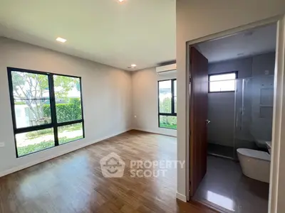 Spacious modern bedroom with ensuite bathroom and large windows overlooking garden.