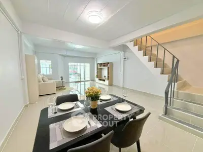 Spacious modern living room with dining area and staircase, featuring elegant decor and natural light.