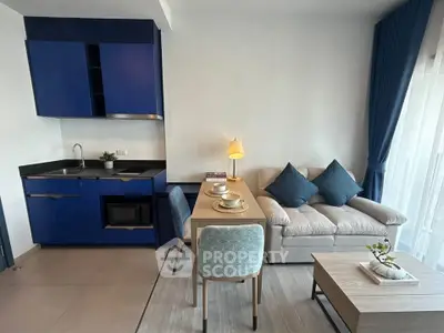Modern open-plan living room with blue kitchen cabinets and cozy seating area.