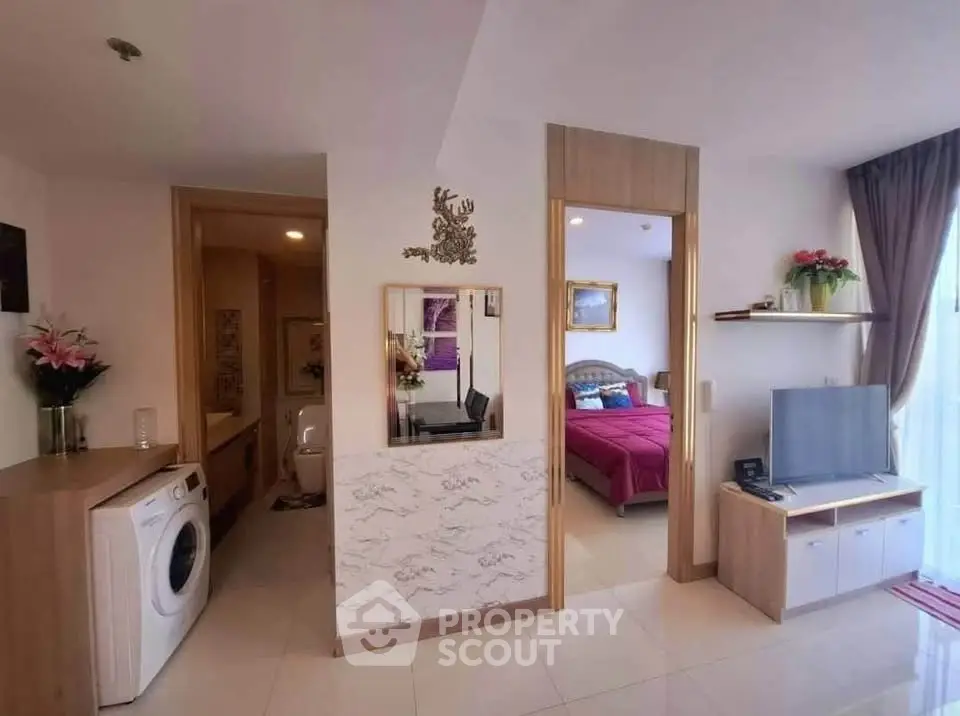 Modern apartment interior with open living space, washing machine, and cozy bedroom view.