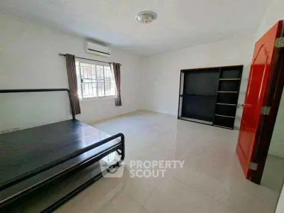 Spacious bedroom with minimalist design and ample natural light, featuring a metal bed frame and built-in wardrobe.
