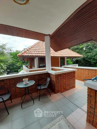 Charming outdoor balcony with brick accents and lush garden view, perfect for relaxation and entertaining.