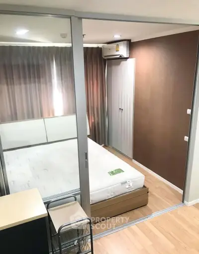 Modern bedroom with sliding glass doors and wooden flooring in a cozy apartment.