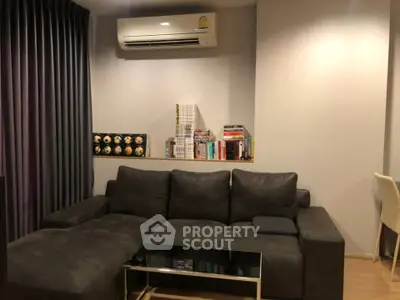 Modern living room with sleek dark sofa and air conditioning, perfect for cozy relaxation.