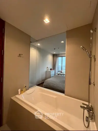 Modern bathroom with bathtub and view into a stylish bedroom