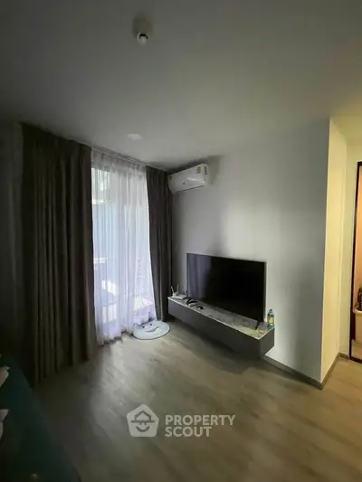 Modern living room with sleek TV setup and natural light from large window.