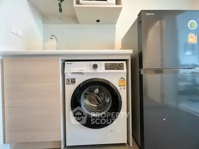 Modern kitchen with washing machine and fridge in compact layout.