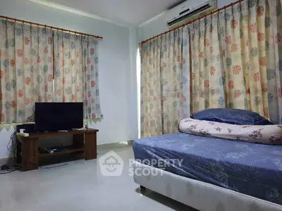Cozy bedroom with TV and air conditioning, featuring floral curtains and a comfortable bed.