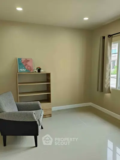 Cozy living room with modern armchair and bookshelf, perfect for relaxation.