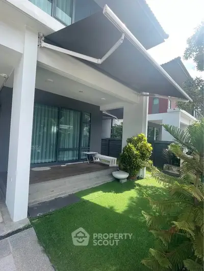 Modern home exterior with retractable awning and lush green lawn