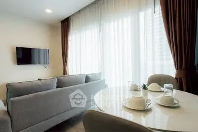 Modern living room with cozy sofa and dining area, featuring elegant curtains and natural light.