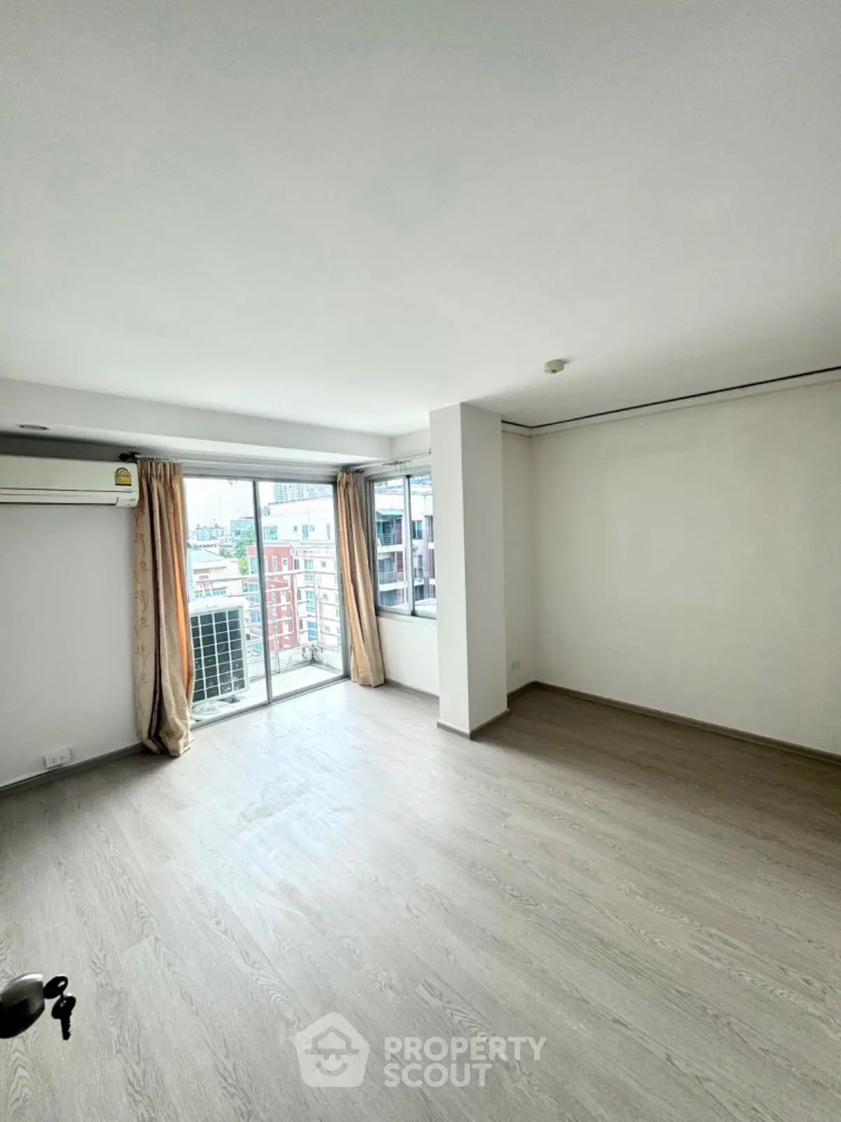 Spacious empty living room with large windows and city view, ready for customization.