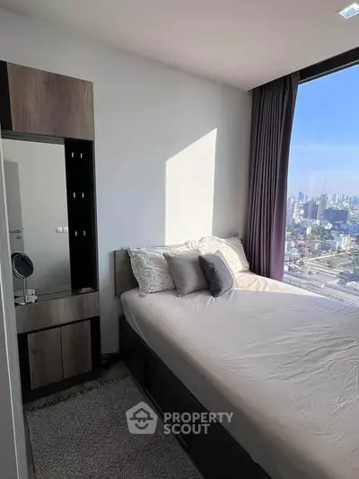 Modern bedroom with city view, featuring stylish furniture and large window for natural light.