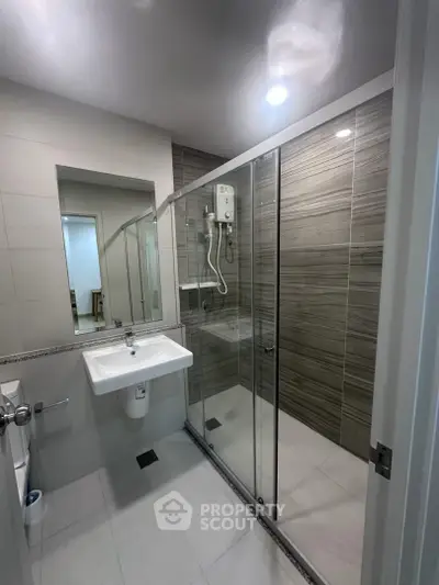 Modern bathroom with glass shower enclosure and sleek fixtures in a contemporary apartment.