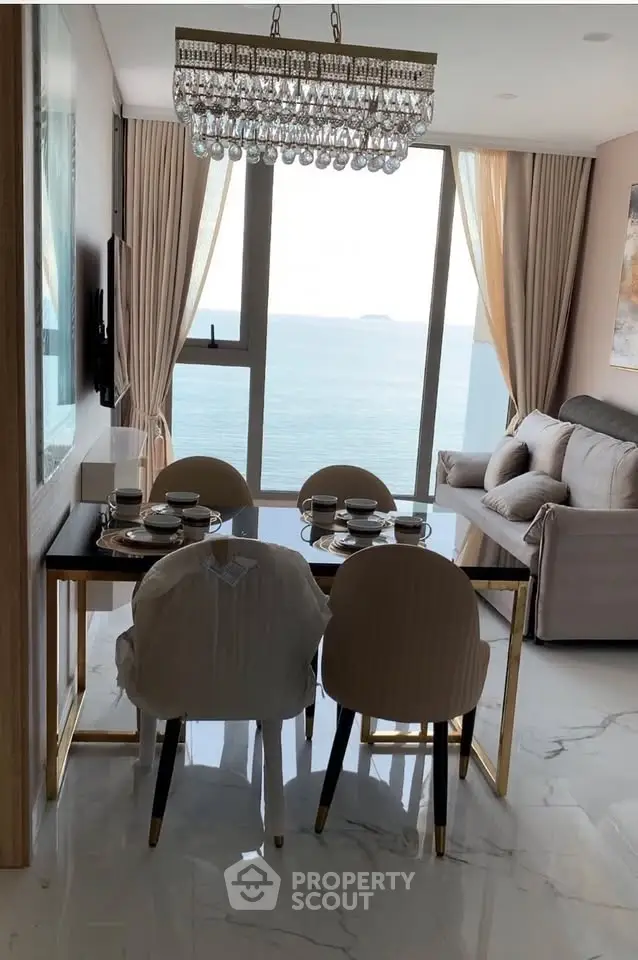 Luxurious dining area with ocean view, elegant chandelier, and modern decor in a high-rise apartment.